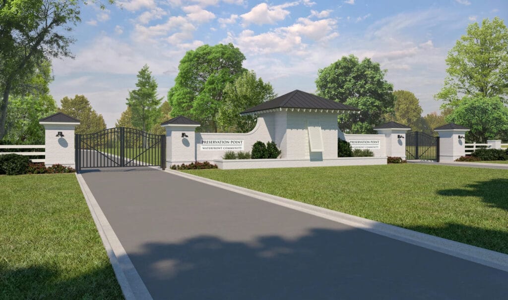 Elegant gated entrance to Preservation Point community with landscaped driveway and modern guardhouse under blue sky.