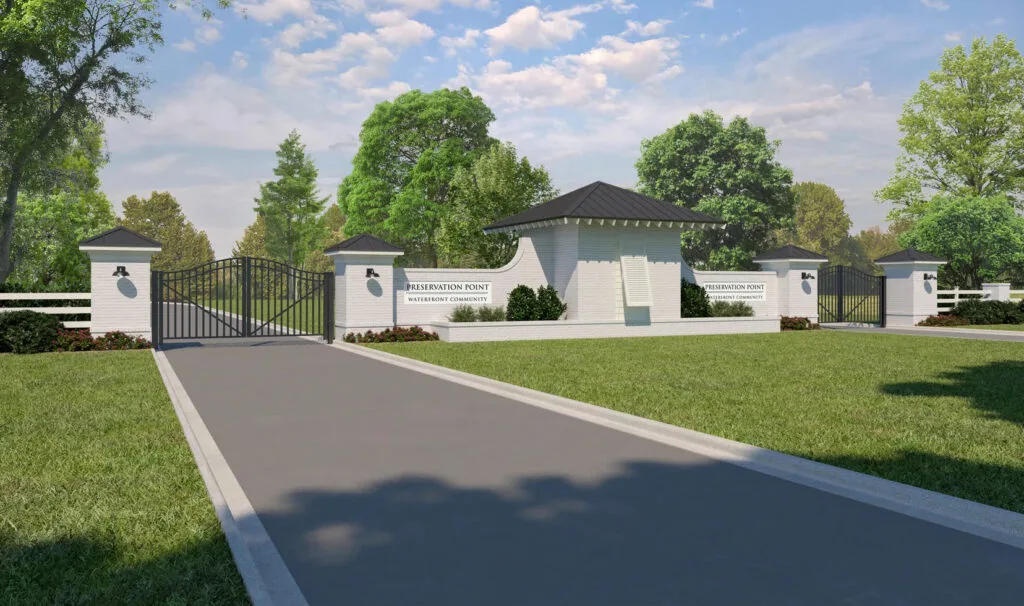 Elegant gated entrance to Preservation Point community with landscaped driveway and modern guardhouse under blue sky.