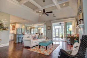 Coastal open-concept living room with white coffered ceiling, hardwood floors, and turquoise accents.