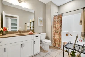 Modern white bathroom with gray walls, beige vanity, and patterned shower curtain.