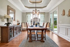 Elegant farmhouse dining room with wooden table, cream chairs, and coffered ceiling.