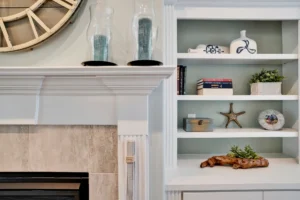 Coastal living room with white fireplace mantel, built-in shelves, and serene beach-inspired decor.