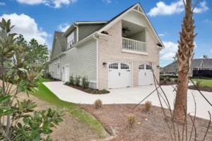 Modern two-story brick and siding home with dual garages, balcony, and landscaped driveway.