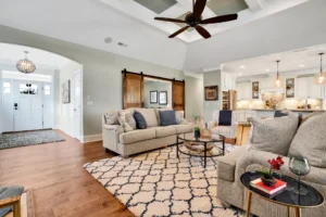 Bright modern farmhouse living room and kitchen with neutral decor, wood flooring, and barn doors.