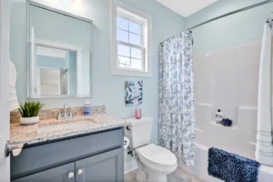 Bright coastal bathroom with blue-gray vanity, granite countertop, and airy modern design.