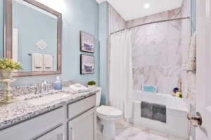 Modern blue and gray bathroom with granite countertop, marble tile, and coastal-inspired décor.