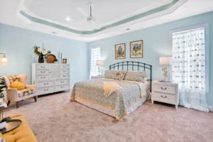 Coastal bedroom with soft blue walls, tray ceiling, and elegant white and gold accents.