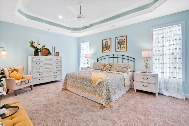 Coastal bedroom with soft blue walls, tray ceiling, and elegant white and gold accents.