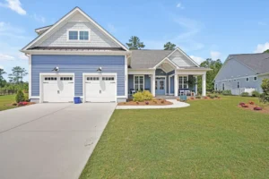 Blue modern farmhouse with white trim, double garage, and inviting front porch in suburban setting.