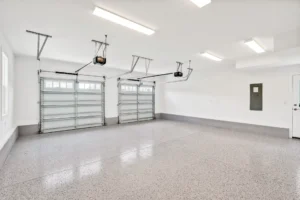 Bright modern two-car garage with white walls, epoxy floor, and fluorescent ceiling lights.