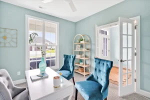 Light pastel blue coastal home office with white desk, blue chairs, and natural sunlight.
