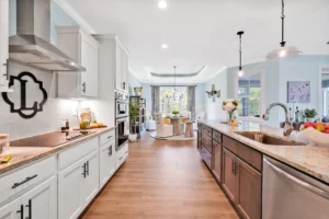 Modern open-concept kitchen with white cabinets, wood floors, and a bright dining area.