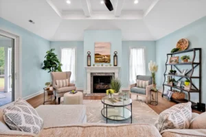 Bright coastal living room with pastel blue walls, white fireplace, neutral sofa, and natural light.