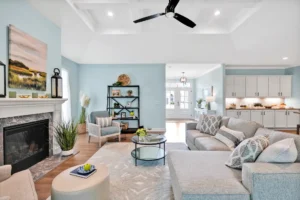 Modern coastal living room with light-gray sectional, white fireplace, and open concept design.