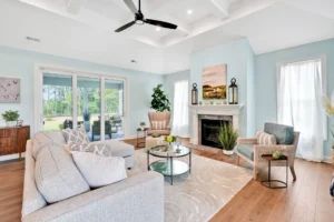 Bright modern coastal living room with gray sectional sofa, turquoise-trimmed fireplace, and natural light.