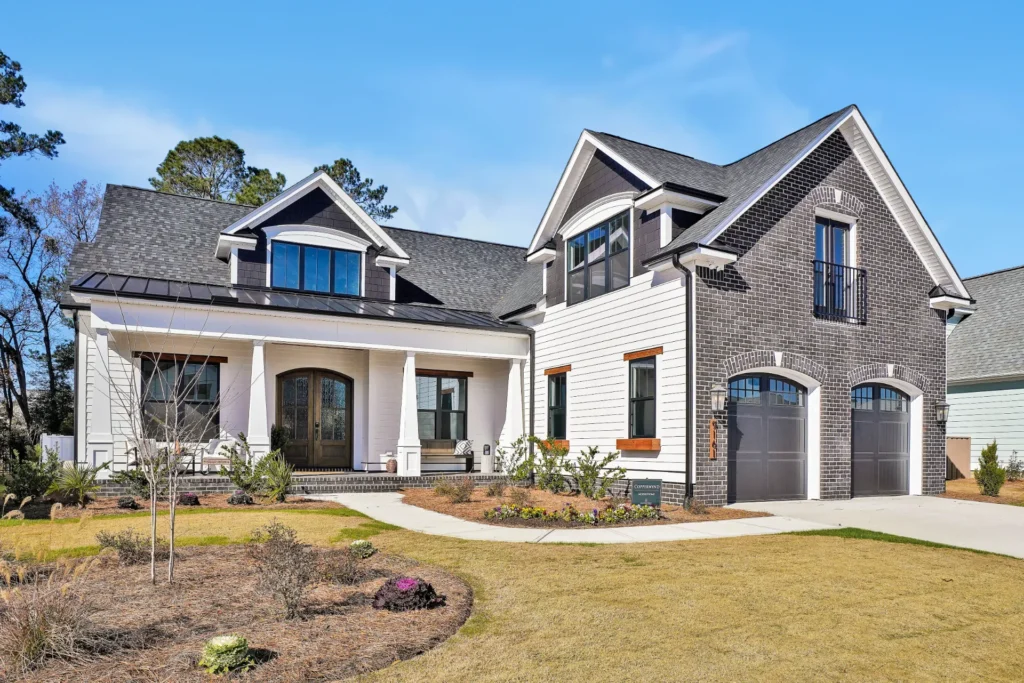 Modern suburban home with white siding, dark brick accents, porch, and double garage.