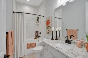 Modern white marble bathroom with black fixtures, coral accents, and elegant minimalist design.