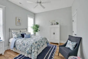 Coastal bedroom with blue and white decor, light gray walls, and bright natural light.
