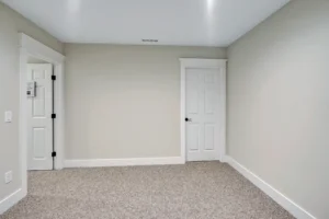 Small modern gray bedroom with white doors, beige carpet, and minimalist bright interior décor.