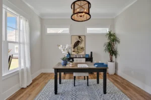 Bright modern home office with wooden desk, gray walls, natural light, and minimalist decor.