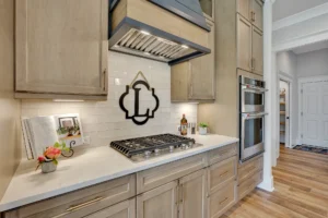 Modern light wood kitchen with white quartz countertops, stainless steel appliances, and warm lighting.