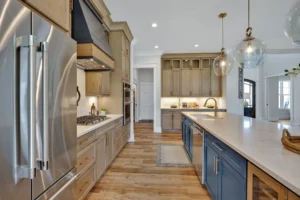 Modern farmhouse kitchen with navy island, brass fixtures, light wood cabinets, and stainless appliances.