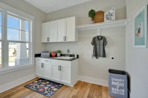 Bright modern laundry room with white cabinets, wood floors, and natural light.