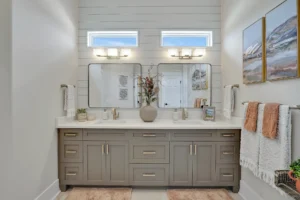 Modern farmhouse bathroom with taupe-gray double vanity, white countertops, and warm natural accents.
