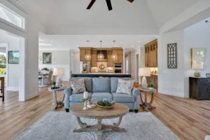 Modern open-concept living room and kitchen with blue sofa, wood accents, and natural light.