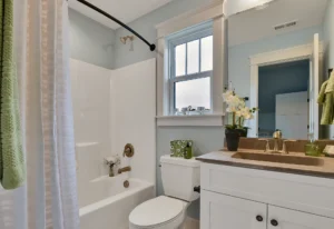 Bright light blue bathroom with gold fixtures, white vanity, and natural light accents.