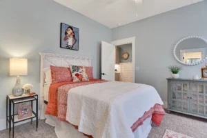 Cozy coral and white bedroom with rustic gray dresser and soft modern decor.