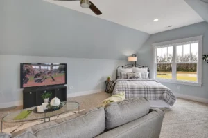 Cozy modern attic bedroom with gray-blue walls, plaid bedding, and bright natural light.