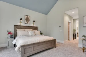 Cozy modern bedroom with wooden bed, white linens, blue ceiling, and soft neutral decor.