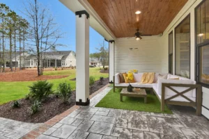 Modern covered patio with wood ceiling, light stone flooring, and cozy outdoor seating area.