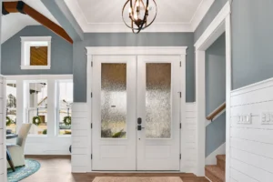 Bright entryway with white double doors, frosted glass, and elegant bronze chandelier.