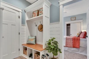 Coastal entryway with white storage bench, woven baskets, wood seat, and beach-inspired decor.