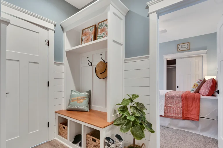 Coastal entryway with white storage bench, woven baskets, wood seat, and beach-inspired decor.