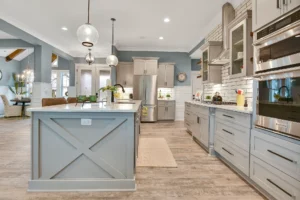 Bright modern farmhouse kitchen with gray cabinets, quartz island, subway backsplash, and pendant lighting.