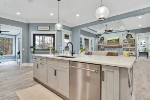Modern open-concept kitchen with quartz island, light wood floors, and connected living room.