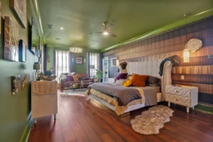 Eclectic green bedroom with modern decor, layered textures, warm lighting, and cozy earthy tones.
