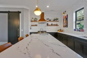 Modern black and white kitchen with marble island, wood accents, and gold lighting fixtures.