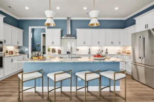 Modern blue and white kitchen with gold accents, sleek island, and stainless steel appliances.