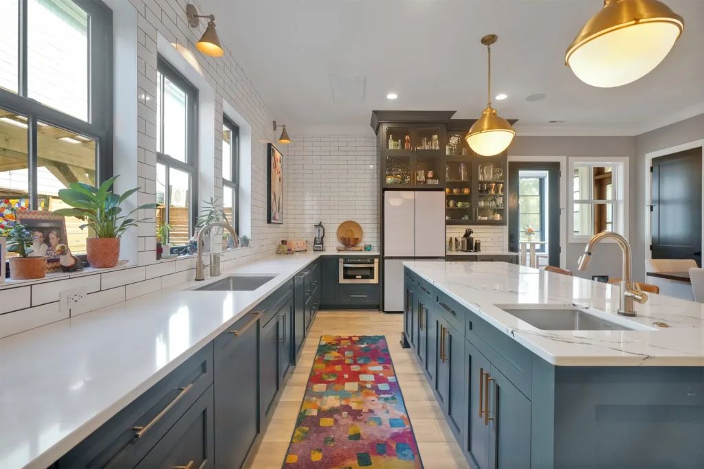 Modern navy and white kitchen with quartz island, gold accents, and pendant lighting.