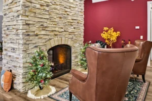 Rustic living room with stone fireplace, leather chairs, and festive Christmas holiday decor.