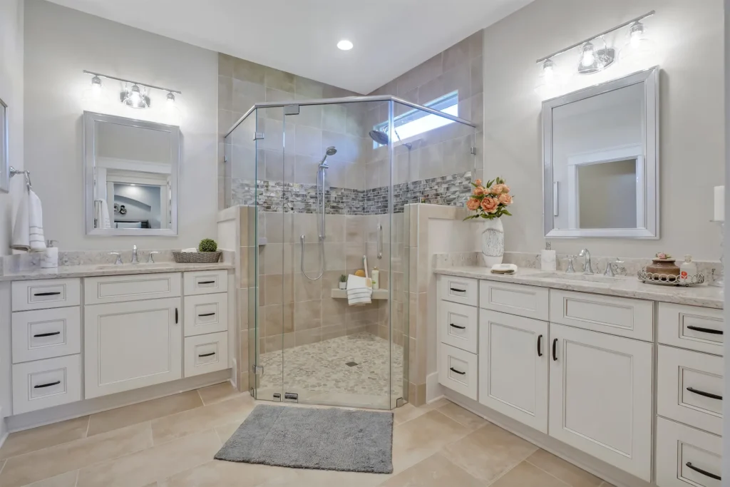 Elegant modern bathroom with frameless glass shower, white vanities, and light tile flooring.