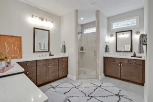 Modern master bathroom with dual vanities, glass walk-in shower, and elegant neutral design.