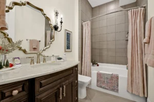 Luxury bathroom with dark wood vanity, marble countertop, and gold fixtures.