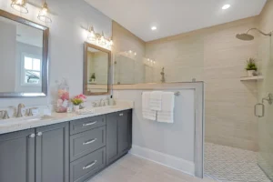 Modern gray bathroom with double vanity, glass shower, and elegant beige tile design.