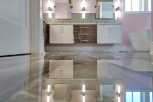 Modern bathroom with glossy reflective floor, white and brown cabinets, warm lighting, and soft pink walls.