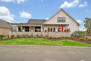 Modern suburban farmhouse with stone porch, red accents, and inviting landscaped front yard.